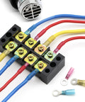 Front view of black screw-terminal block with color-coded heat-shrink wire connectors and nearby ring/spade terminals.