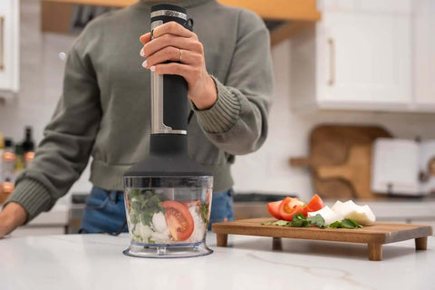 Professional Grade Commercial Blending Machine With A Badass 1800 Watt Motor And Dead Simple Variable Speed Settings For Top Shelf Bar Mixes And Cafe Kitchens In Rust Proof Stainless Steel with vegetables in use on a countertop