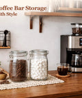 Glass Canister Set 34 Oz Each, 3 Pack Clear Jars For Coffee Bar Countertop, filled with coffee beans and sugar cubes.