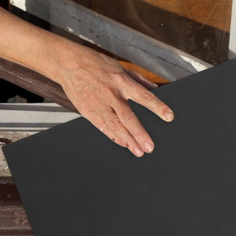 Hand placing 10-Pack Super Fine Carborundum Sandpaper on wooden surface for metal and plastic project.
