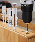Set Of 100 White Plastic Wall Expansion Anchors 2.5 By 0.7 Cm Hollow Wall Plugs for drywall mounting next to drill.