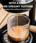 Slick Trail Ready Portable Manual Espresso Maker With Adjustable Temp And Nine Bar Pressure For Straight Up Creamy Lattes On The Go Stainless Steel Hand Pump Coffee Brewing Gear brewing espresso into a glass measuring cup.
