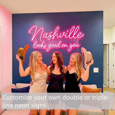 Three women smiling in front of "Nashville looks good on you" pink Personalized Neon Sign For Weddings And Events Dope Custom LED Light Sign With Your Name Or Logo For Bars Salons Offices And Lounges In 16 To 60 Inches Ready To Impress