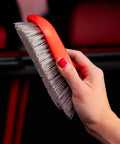 Hand holding red Stiff Bristle Carpet And Upholstery Scrub Brush For Auto And Home Use, Heavy Duty Grime Buster