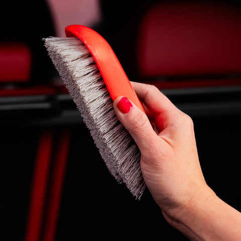 Hand holding red Stiff Bristle Carpet And Upholstery Scrub Brush For Auto And Home Use, Heavy Duty Grime Buster