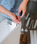 Person installing Six Piece Set Of 19mm White Plastic Drawer Rollers Featuring Slick Cabinet Pulleys on a drawer.