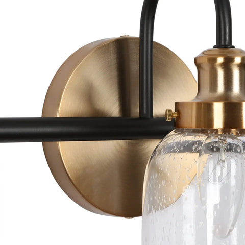 Close-up of Modern 3 Light Seeded Glass Vanity Light Fixture In Matte Black And Brushed Brass Finish With A Circular Backplate.
