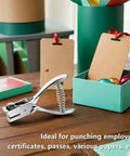 Heavy Duty All Metal Badge Hole Punch for ID Cards with 15x3mm slots, placed on a table next to boxes and tags, ideal for PVC badges.