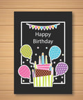 Birthday card with colorful balloons and cake on a black background showing "Happy Birthday" text, displayed on wooden surface.