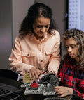 Two people building a model with Gear Builder Bulk Kit For Brick Creations: Axles, Gears, Universal Joints, and Wheels.