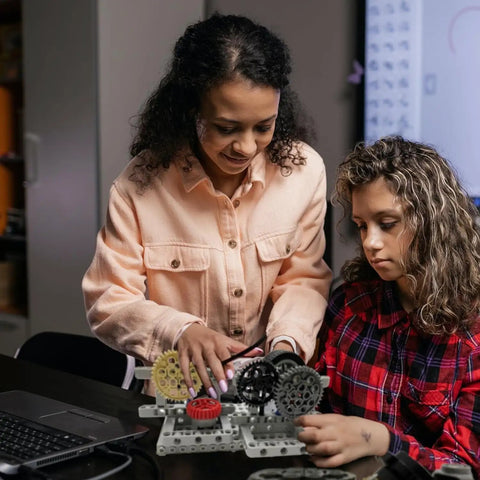 Two people building a model with Gear Builder Bulk Kit For Brick Creations: Axles, Gears, Universal Joints, and Wheels.