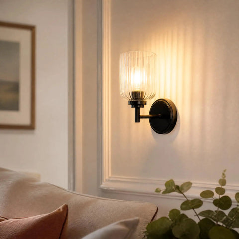 AOIOUR 10.4" 1‑Light Farmhouse Vanity Wall Sconce, Ribbed Glass Matte Black mounted beside a couch, softly illuminating the room.