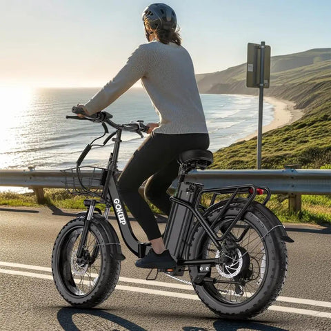 Woman riding Beast Electric Bike For Adults With 1800W Peak Motor, 86 Mile Range, 52V 18.2Ah Removable Battery along coastal road.