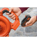 20V Max 15 Ah Lithium Ion Rechargeable Power Tool Battery held next to an orange leaf blower for easy installation.