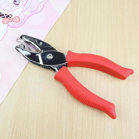Square Hole Paper Punch 3 Sixteenth Inch Handheld Puncher with red soft grip handle on a wooden table