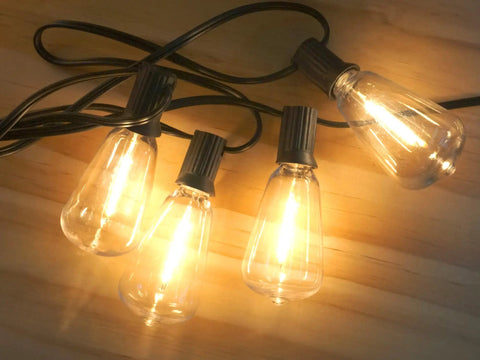 Outdoor String Lights 30ft With 25 Plus 2 Spare LED Filament Bulbs, Dimmable, Shatterproof, Edison Vintage Style glowing warm on wood