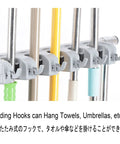 Movable Broom And Mop Holder Stainless Steel Rack for multiple tools with folding hooks close-up.
