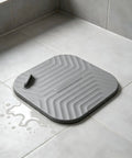 Shower Drain Cover Tub Stopper Square Silicone Floor Drain Cover in gray, 5.9x5.9 inches, on tile with water.