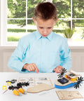 Child assembling Remote Control Boat Building Kit For Kids Ages 8-12, Paddle Boat Fun, STEM Science Project with wooden parts on table.