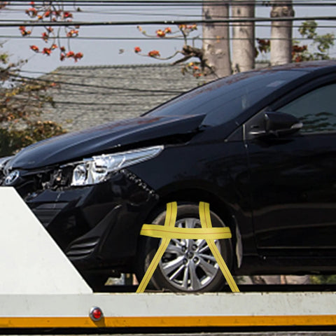 Lifting sling strap installed around the front wheel of a black car on a tow trailer; yellow nylon, 6 ft by 2 in.