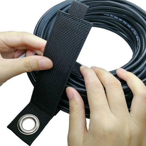 Hands securing a coiled cable with a black heavy duty storage strap from the 10 pack assorted for extension cord organization and cable management.