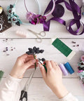 Hands crafting bouquet using Must Have All In One Floral Tape And Wire Toolkit for DIY Bouquets And Arrangements, seen on table.