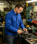 Man wearing Badass Men's Premium Pure Cotton Long Sleeve Utility Work Shirt With Heavy Duty Pockets working at a shop.