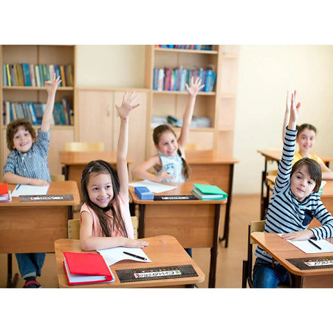 Students using 48 Desk Name Tags Classroom Set With Traditional Manuscript Nametags in a classroom, showing colorful designs.