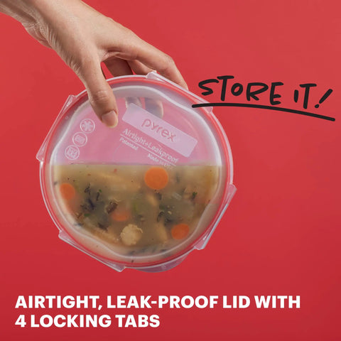 Hand holding a round glass container from Freshlock 14 Piece Glass Food Storage Containers Set with airtight lid, filled with soup.