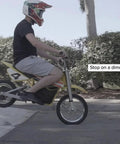 Person riding yellow dirt bike demonstrating use of Front Brake Disc Rotor For Razor MX500 MX650 Electric Dirt Bikes Six And One Quarter Inch Outside Diameter 159mm Six Mounting Holes Heavy Duty Front Rotor For Dirt Rocket Brakes in action.