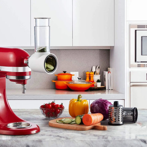 Red stand mixer with all in one slicer shredder attachment, veggies on countertop in modern kitchen, focus on prep station