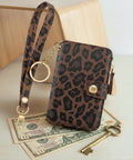 Streamlined Rfid Blocking Keychain Wallet With Genuine Leather Wrist Strap resting on bills, featuring a leopard print design.