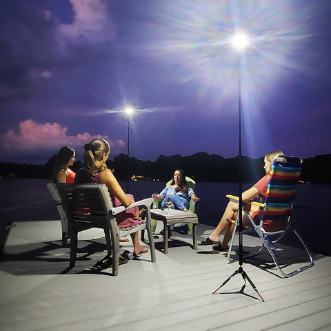 Group sitting under Beast Bright Telescoping Area Light With 8 Foot Extension And Removable Flashlight on a dock at night