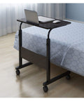 Adjustable Rolling Laptop Table With Smooth Ride Wheels For Bed Sofa Or Living Room Mobile Workstation beside a bed with laptop and mouse.