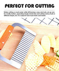 Stainless steel wavy crinkle cutter with orange wooden handle, front view on cutting board beside crinkle-cut potatoes.