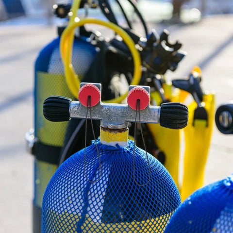 Scuba tank with red diving tank valve threaded plug with cord cover, surrounded by gear and blue netting.