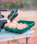 Tough 12-Egg Plastic Carrier With Locking Lid, Molded Handle, And Secure Fit For Camping, Road Trips, And Meal Prep on table