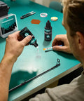 Essential Fishing Rod Repair Kit With Strong Epoxy Glue, user applying glue to fishing rod on green table.