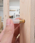 Installing Brass Shelf Support Pins One Quarter Inch With Rubber Covers into wooden shelf hole.