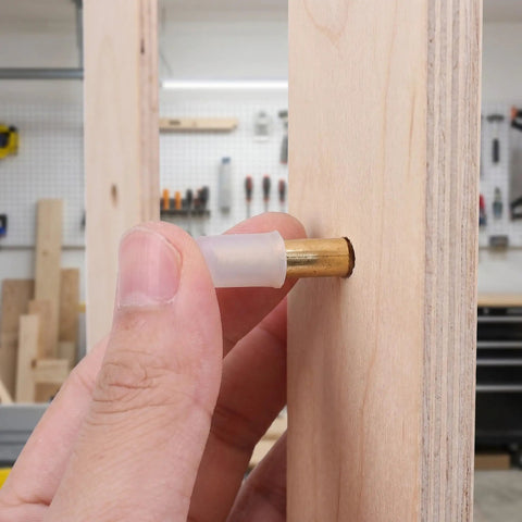 Inserting heavy duty brass shelf pin with rubber cover for modern cabinets and closets in wood for stable multi shelf support.