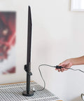 Star Wars The Mandalorian Darksaber 24-Inch LED Desk Light Lamp for Fans being plugged in on a patterned tabletop.
