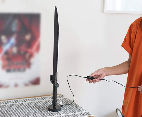 Star Wars The Mandalorian Darksaber 24-Inch LED Desk Light Lamp for Fans being plugged in on a patterned tabletop.