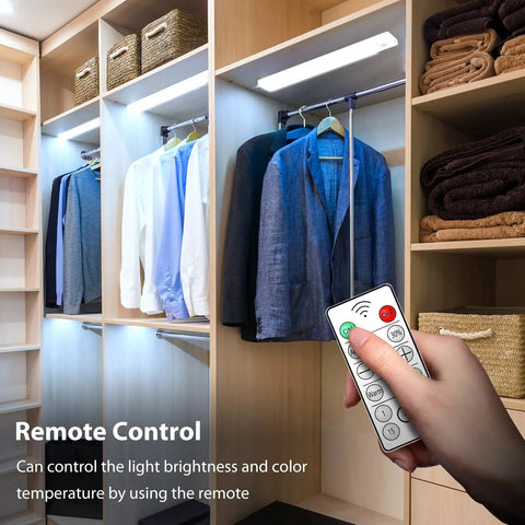 Person using remote control to adjust 11.8 Inch Under Cabinet Light With Motion Sensor in closet, illuminating hanging clothes