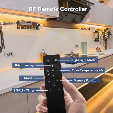 Hand holding remote control for Under Cabinet Lighting Kit With 6 Pack 12 Inch LED Strips, showing kitchen installation.