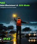 Person in orange jacket holding IPX5 water-resistant lantern with SOS mode by rocky shoreline at night