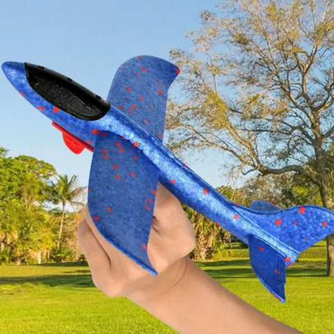Blue foam glider plane held in hand in park, 7.68 inch, lightweight, suitable for outdoor play. Foam Gliders For Backyard Fun And Outdoor Play Lightweight 7.68 Inch Foam Launchers For Kids Totally Easy Toss Soaring Summer Recreation Beach And Park Entertainment Safe Compact Planes That Boost Hand Eye Coordination.