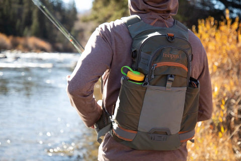 Angler near river wearing Ridgeline Fly Fishing Backpack For Real Anglers, A Lightweight Tackle Pack With Hydration Pass Through, Foam Shoulders