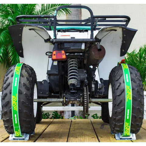 ATV secured with Fastrap Tie Down Kit, showing straps on tires for 8 to 27 inch wheels on a wooden deck trailer.
