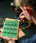 Person using Advanced SMD and SMT Soldering Practice Kit for Pro Electronics Hobbyists DIY Training Board With 313 Components And 1079 Precision Solder Points EK8489, showing precise detail work on the board.