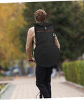 A person riding a scooter with a Heavy Duty Black Drum Bag Made For Open Road Rhythms on their back, showcasing its sleek design.